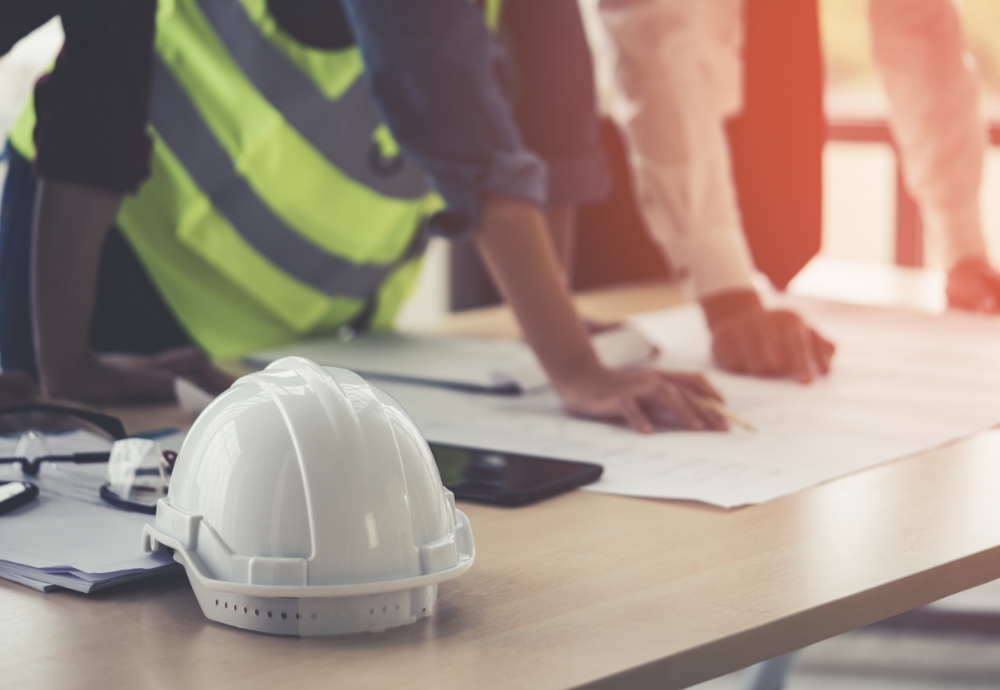 workers around a table with a construction hat